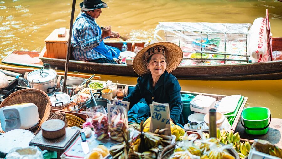 Smiling Thai vendor selling fresh produce from a boat at floating market