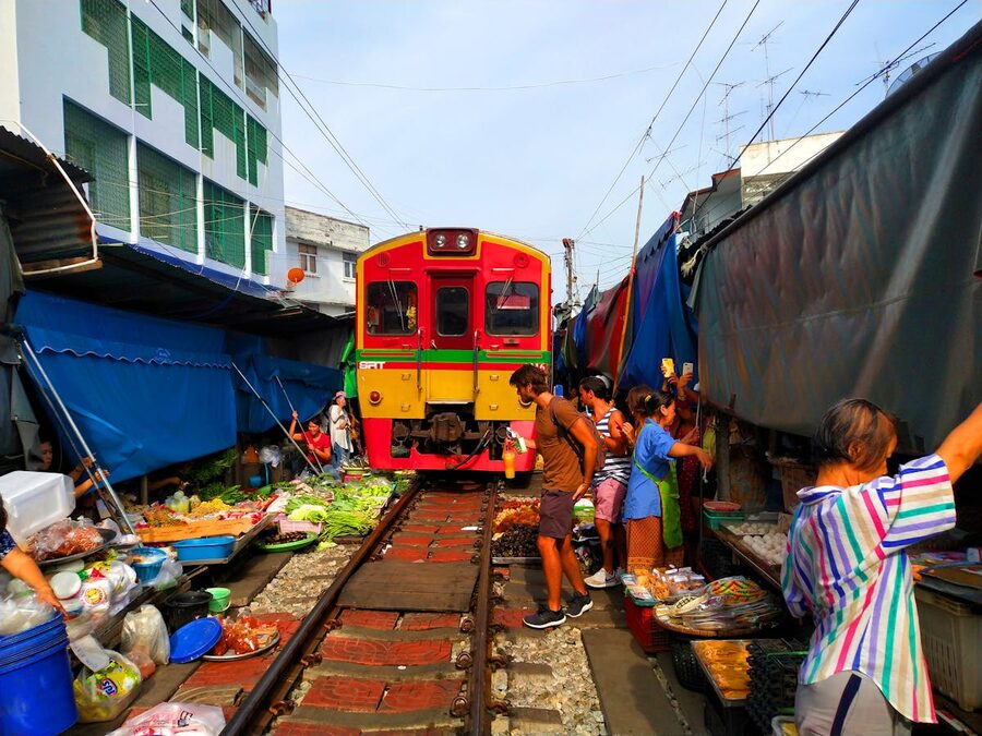 A colorful train passing through Maeklong Railway Market