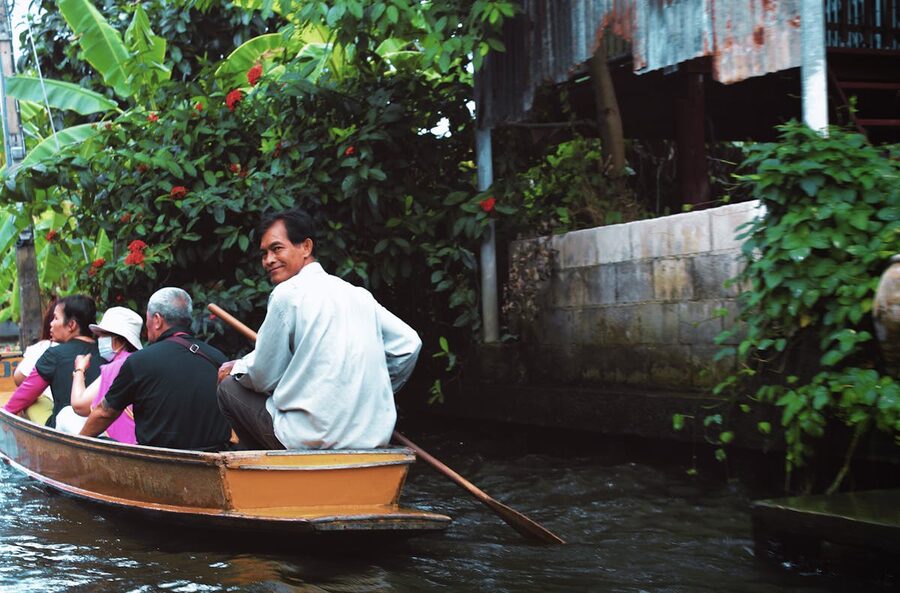 People on a traditional boat ride through lush Bangkok canals