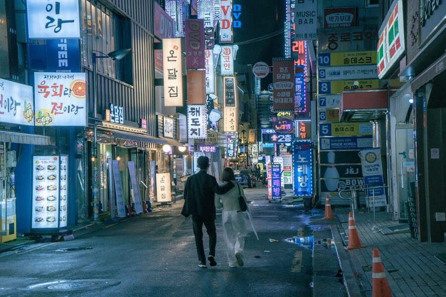 Tourists walking through neon-lit Seoul street in Gangnam at night