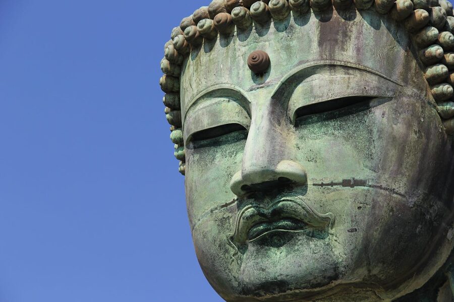 Detailed close-up of the Kamakura Daibutsu Buddha statue under clear blue sky