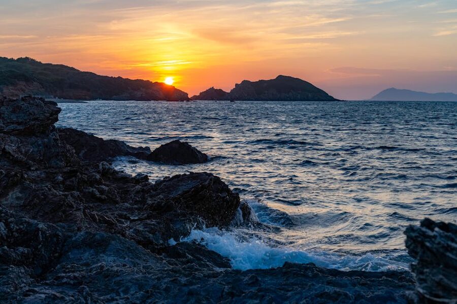 Rocky sea shoreline at sunset with waves