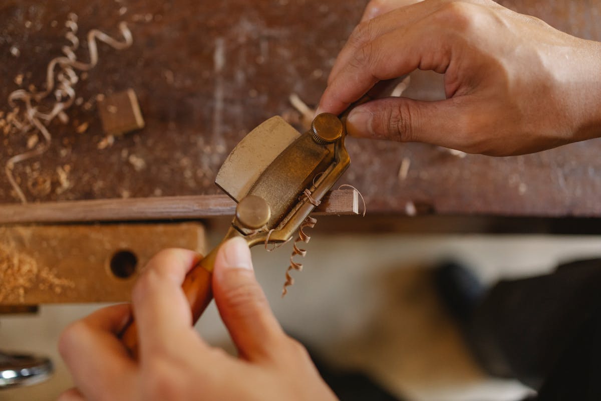 High angle view of a carpenter carving a wooden detail with a router plane on a workbench