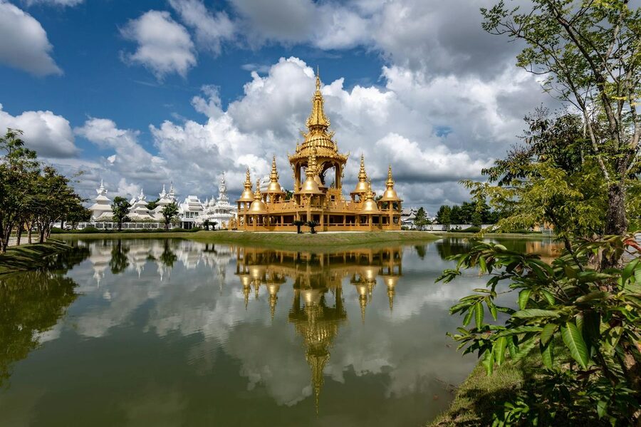 Golden ornamental building near the White Temple reflecting in lake