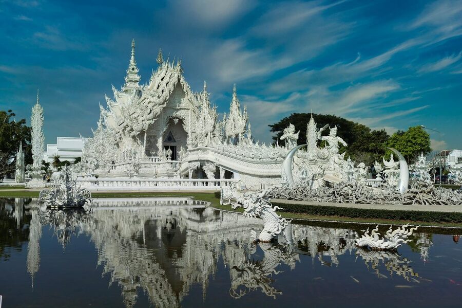 Wat Rong Khun White Temple reflected in clear water at Chiang Rai Thailand