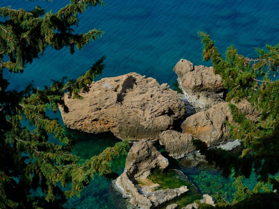 Clear turquoise water over volcanic rocks in a sheltered Bali cove on a calm morning