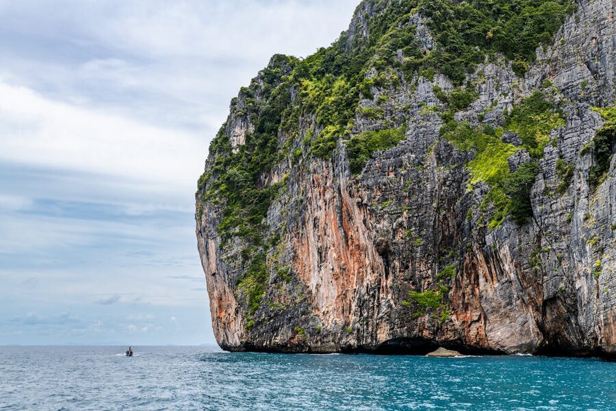 Dramatic limestone cliff rising from turquoise sea in Phuket Thailand