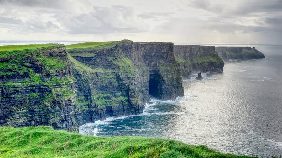 Wide green panorama of the Cliffs of Moher with sea below