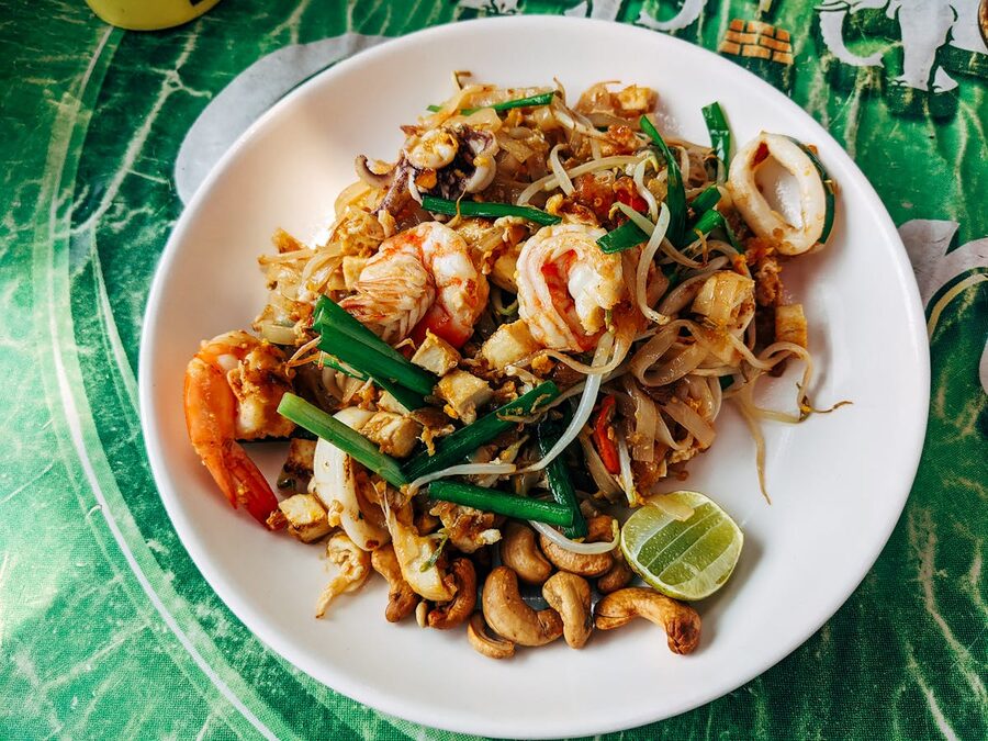 Close-up of pad thai with shrimp, vegetables, and lime on a plate