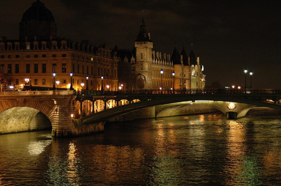 Conciergerie illuminated at night along the Seine in Paris