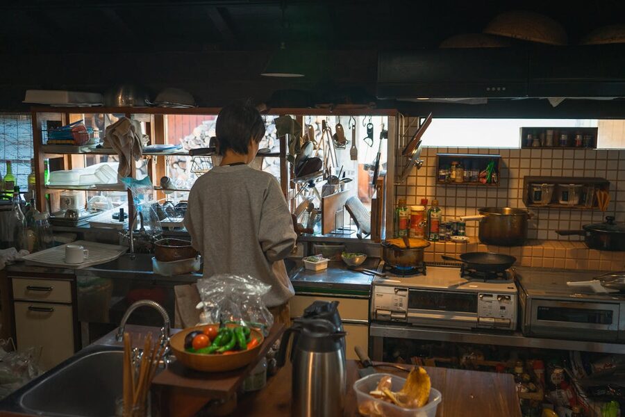 A person cooking in a traditional Japanese kitchen surrounded by cooking tools and ingredients