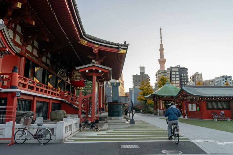 A cyclist near the historic Sensoji Temple in Asakusa with Tokyo Skytree visible in the background