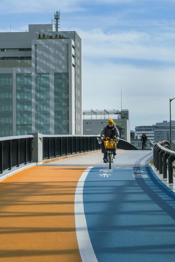 Cyclist rides on a colorful blue and orange bike path in Tokyo