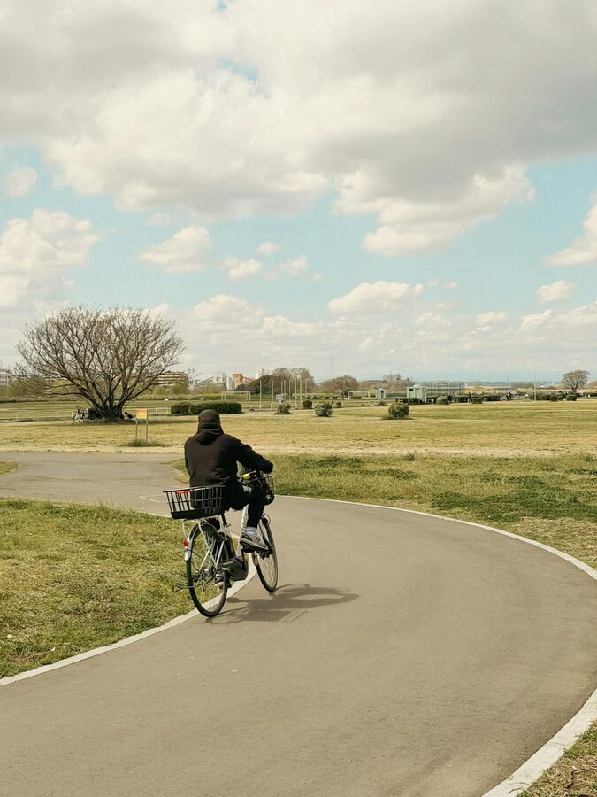 Lone cyclist riding through a quiet tree-lined park in Tokyo