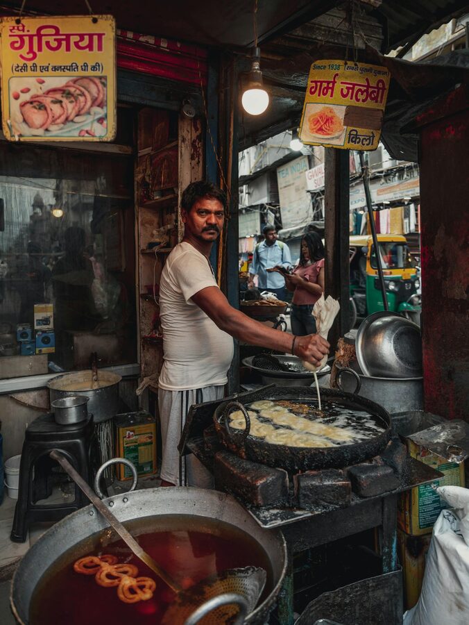 Delhi street vendor preparing hot jalebi in a large pan of ghee