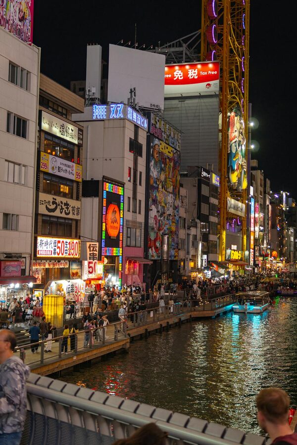 Night view of Dotonbori Canal in Osaka with crowds and colorful neon reflections