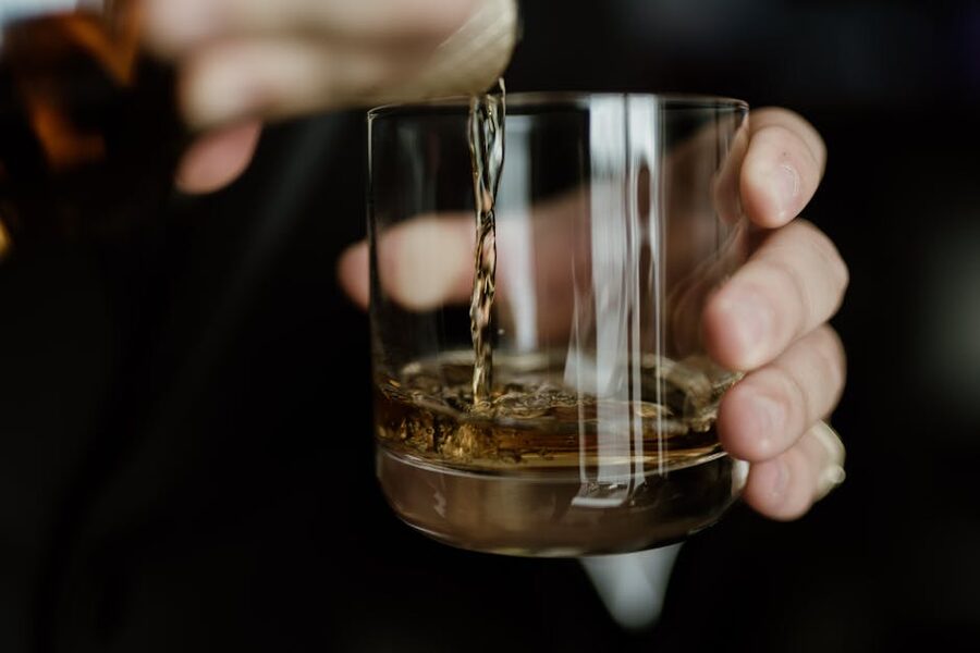 Hand pouring whiskey into a tasting glass
