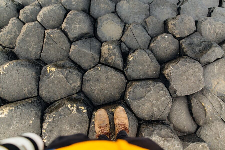 Boots standing on the hexagonal basalt columns of Giants Causeway showing the joint pattern