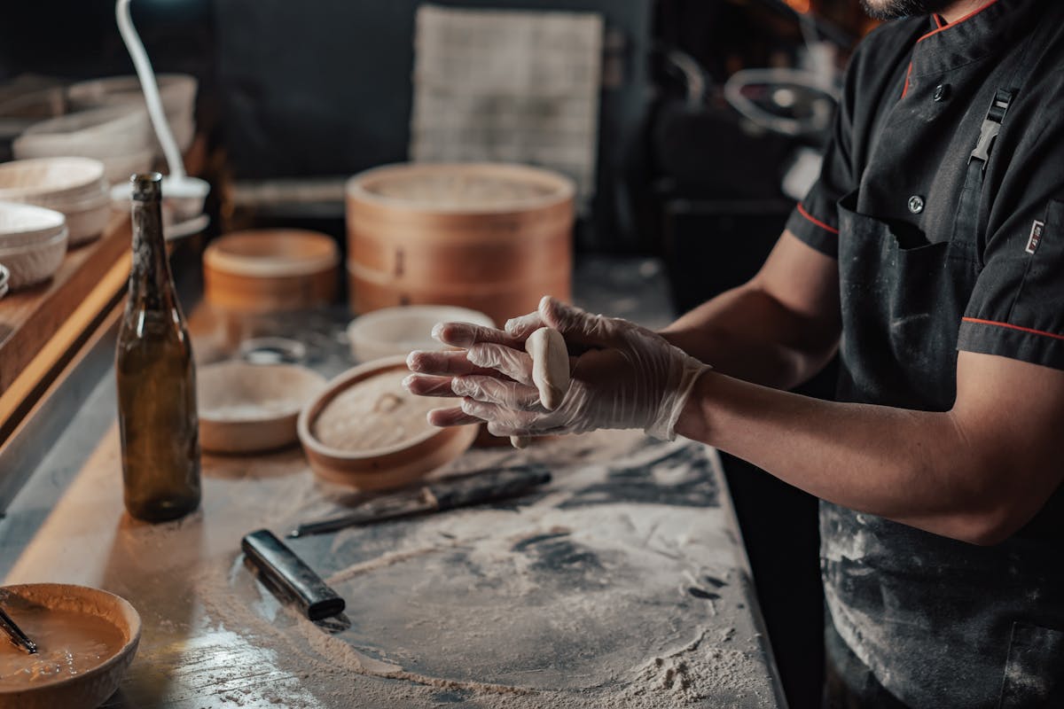 Close-up of hands carefully crafting dumplings on a floured surface in a dimly lit kitchen