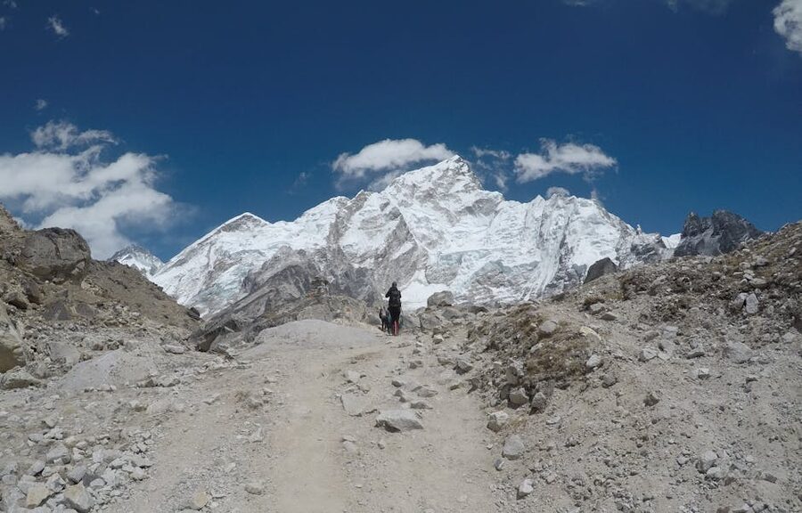 Lone trekker on a rugged path with Everest in the background