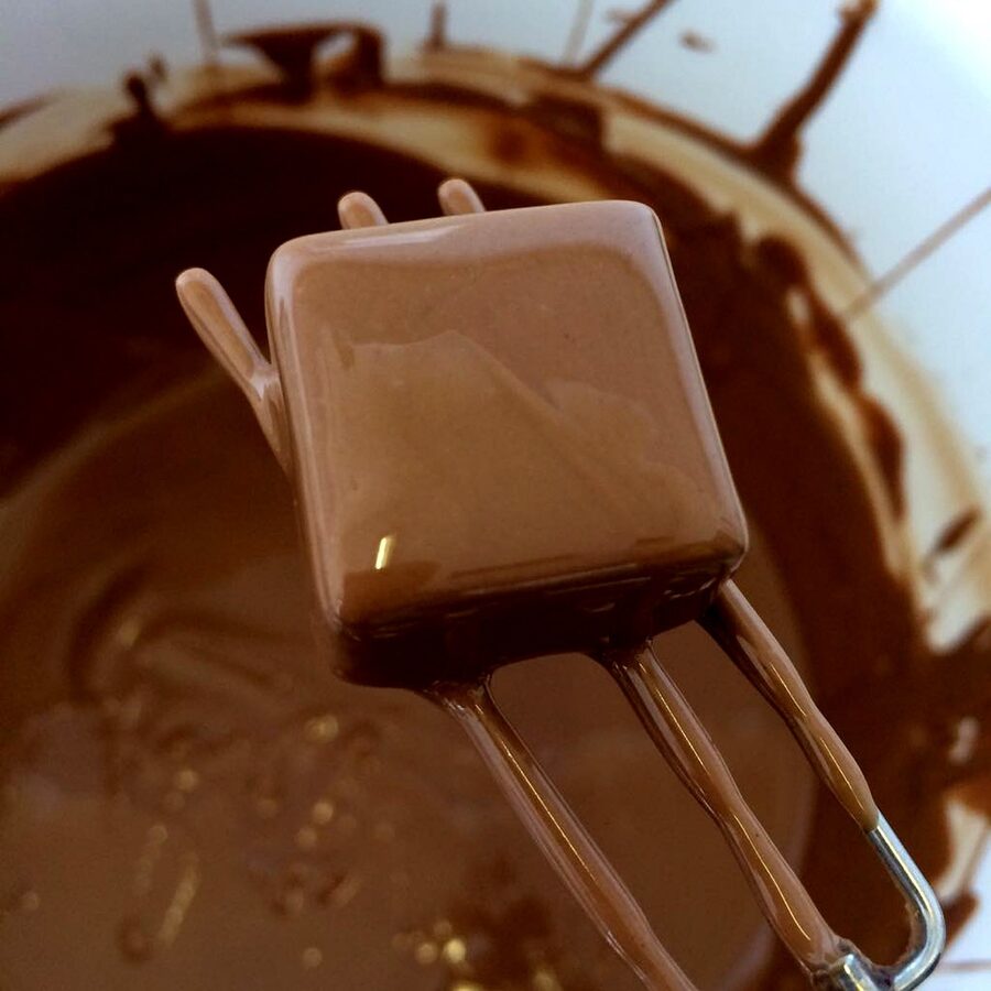 Hand dipping chocolate with fork