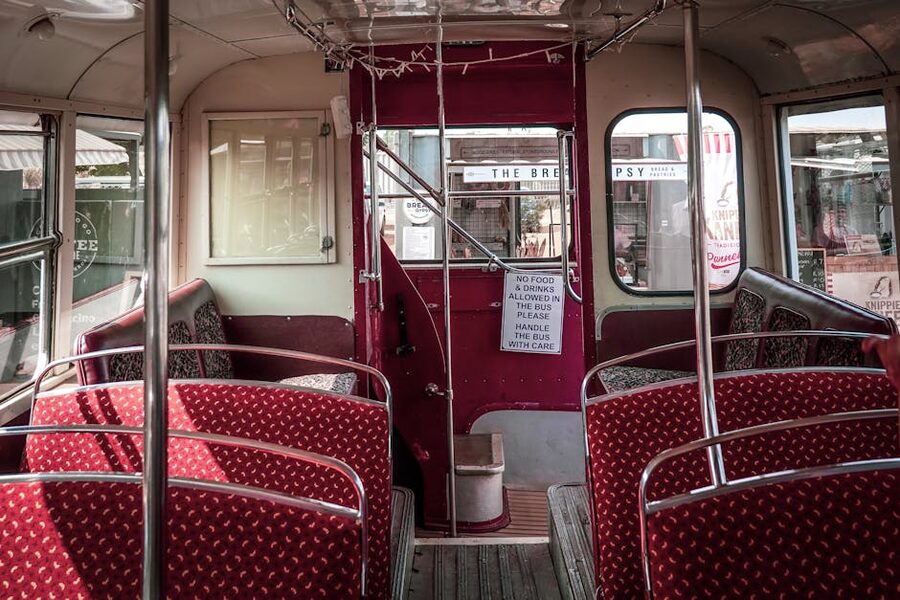 Inside a vintage double-decker bus with red patterned seats