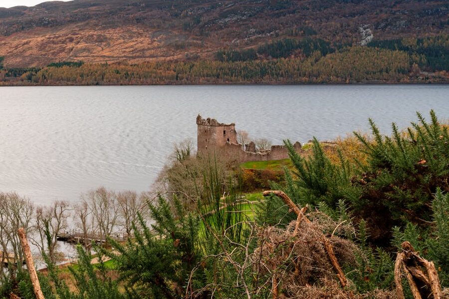 Urquhart Castle on Loch Ness with green ridge