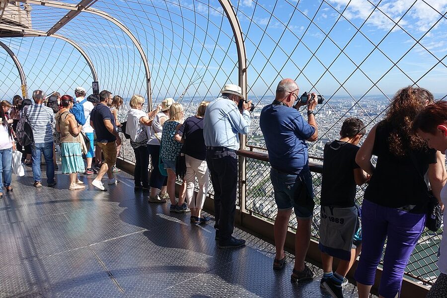 Eiffel Tower summit observation deck with visitors looking over Paris