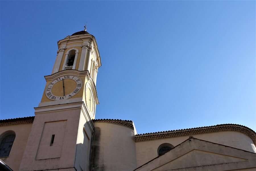 Yellow bell tower of the Eze parish church against blue sky