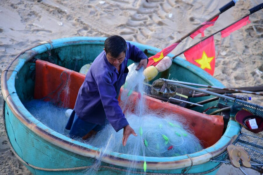 Fisherman arranging nets in a round Vietnamese basket boat