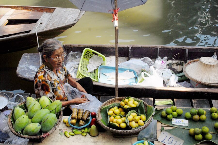 Elderly woman selling fresh fruits at a floating market in Bangkok