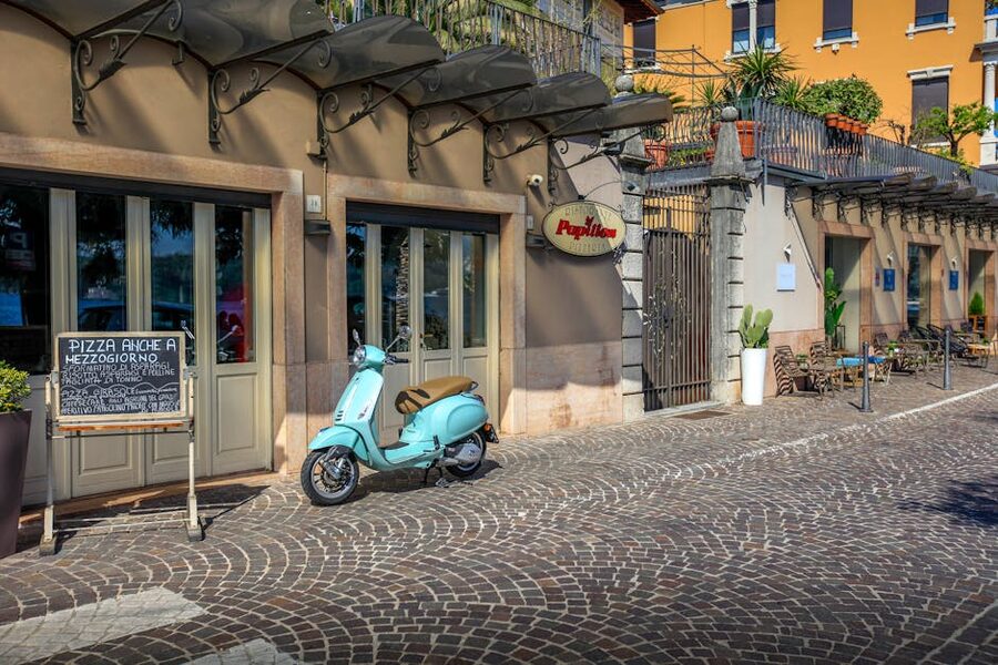 Italian street with a parked Vespa and cafe seating