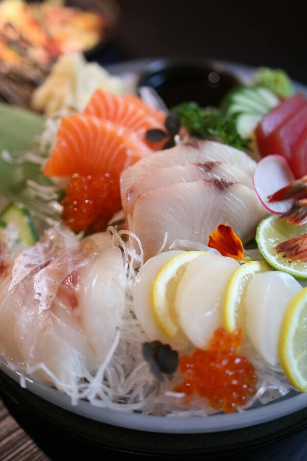 Assorted fresh sashimi with lemon slices on a decorative plate
