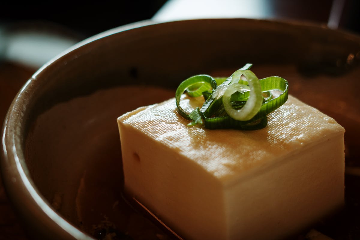Fresh tofu garnished with sliced green onions served on a plate