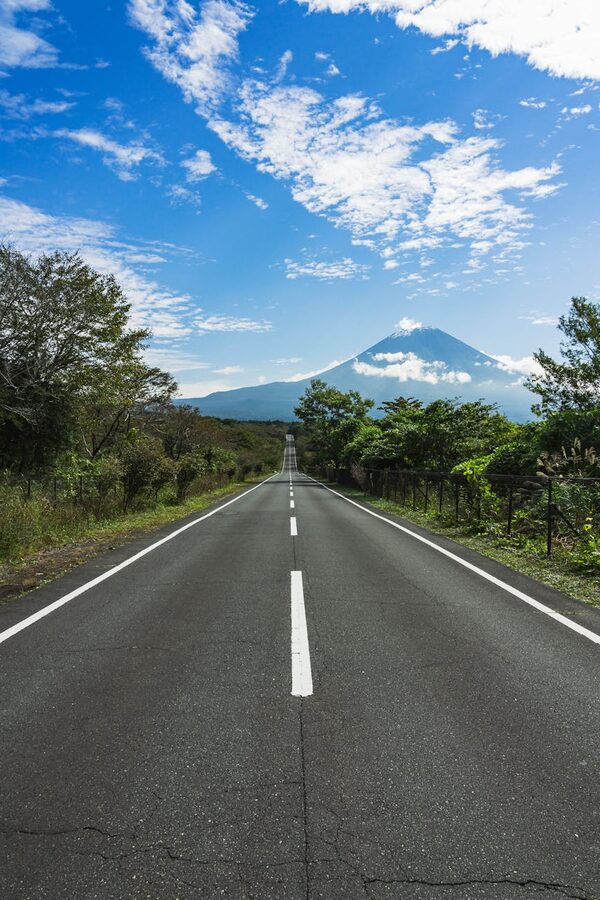 A straight highway with clear skies leading towards the iconic Mount Fuji