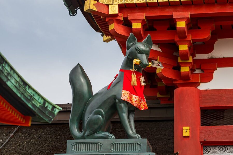 Stone fox statue with red bib at Fushimi Inari Shrine Kyoto