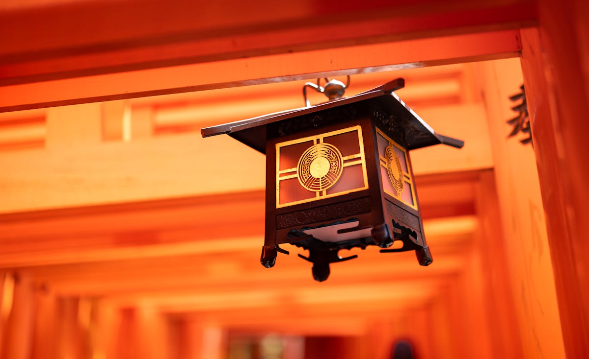 Traditional stone lantern beneath orange torii gates at Fushimi Inari