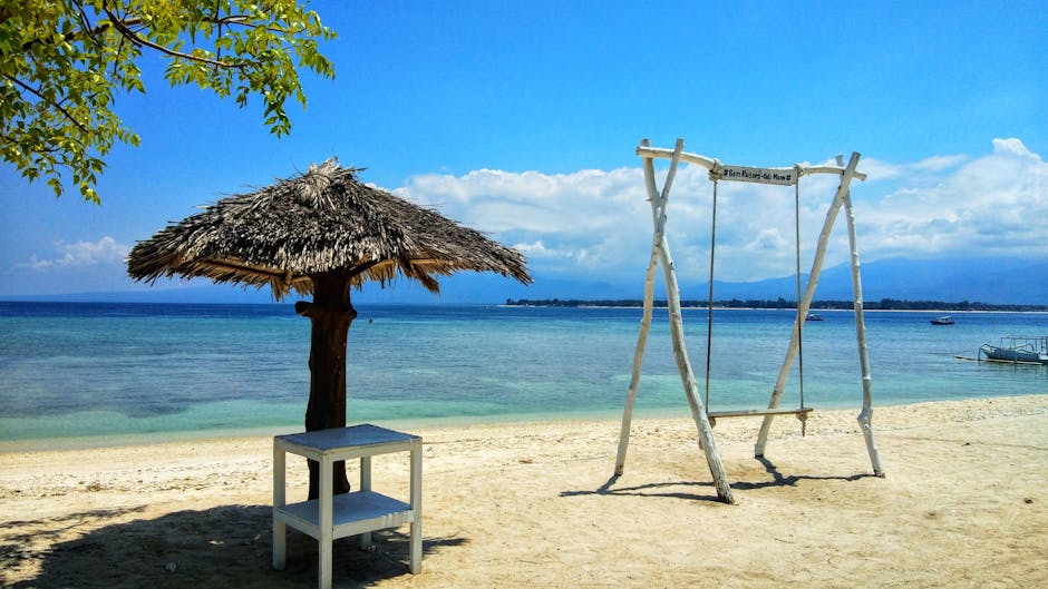 Beach scene with a wooden swing and thatched umbrella in West Nusa Tenggara