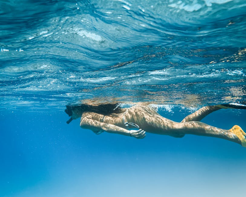 A woman snorkeling in crystal clear tropical water with underwater visibility