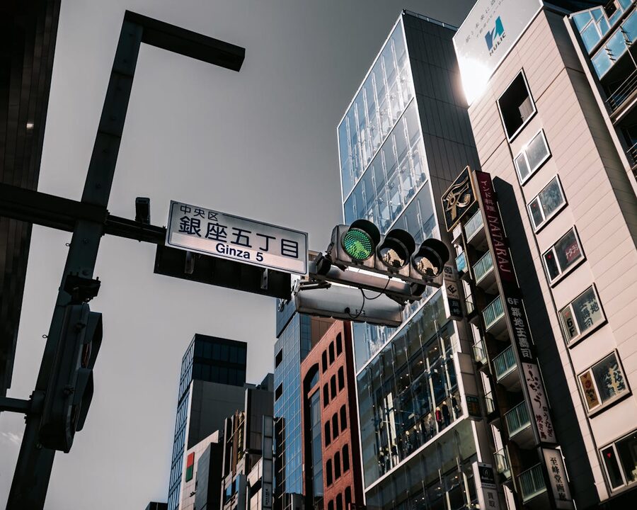 Urban scene at the Ginza 5 intersection in Tokyo showing skyscrapers and traffic lights under a clear sky