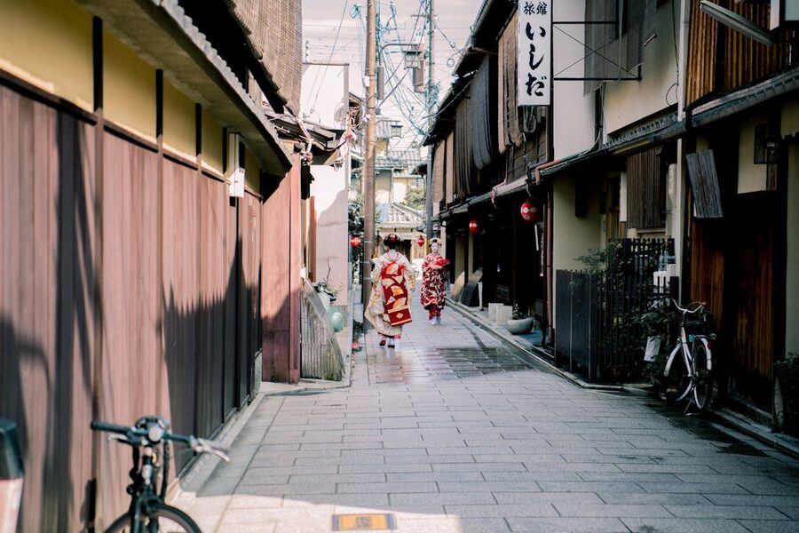 Two geisha in traditional attire walking along a historic Kyoto street