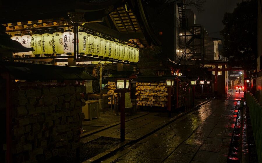 Atmospheric night scene of a Kyoto shrine area with warm lantern light