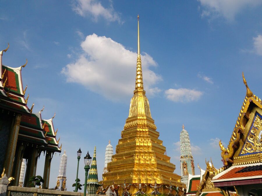 Majestic golden stupa at the Temple of the Emerald Buddha under a bright blue sky in Bangkok