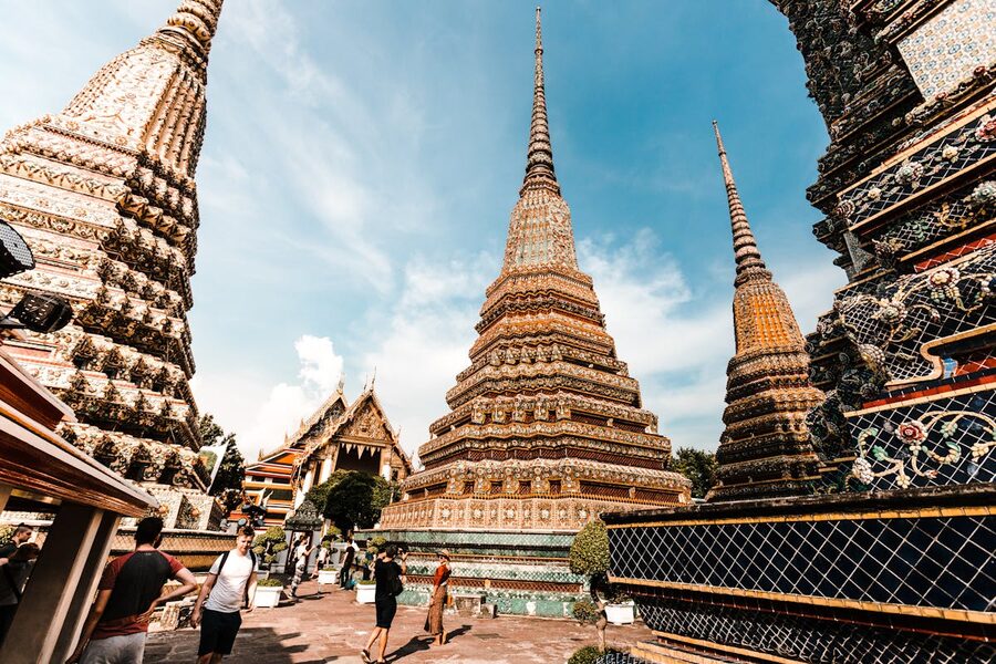 Colorful traditional pagodas at Wat Pho temple under a bright blue sky in Bangkok
