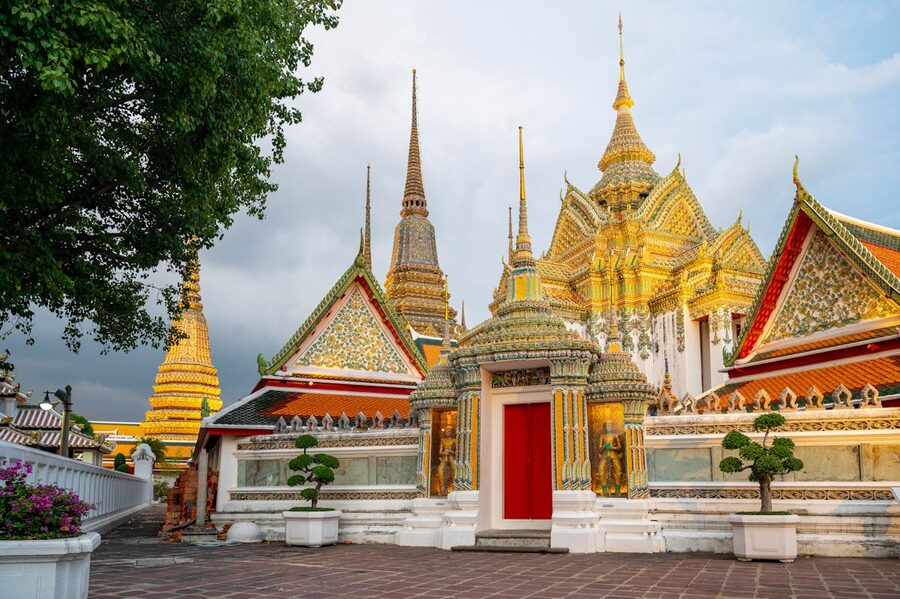 Ornate multi-tiered roof of Wat Pho temple against a bright blue sky in Bangkok