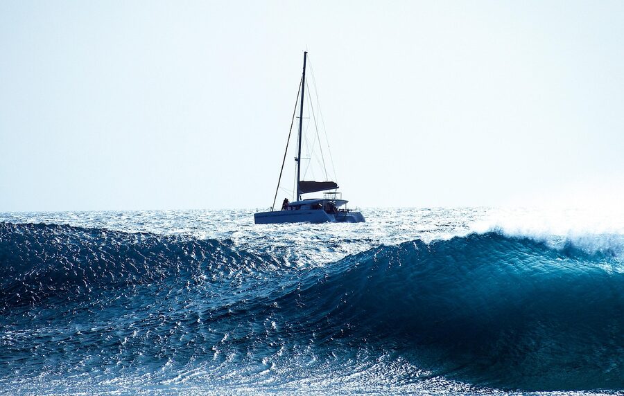 Sailing catamaran on Atlantic Ocean waves under blue sky