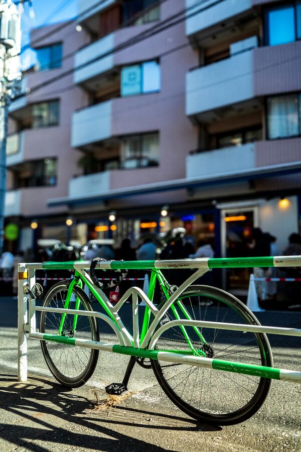 Colorful green bicycle parked on a Shibuya street with modern buildings in background