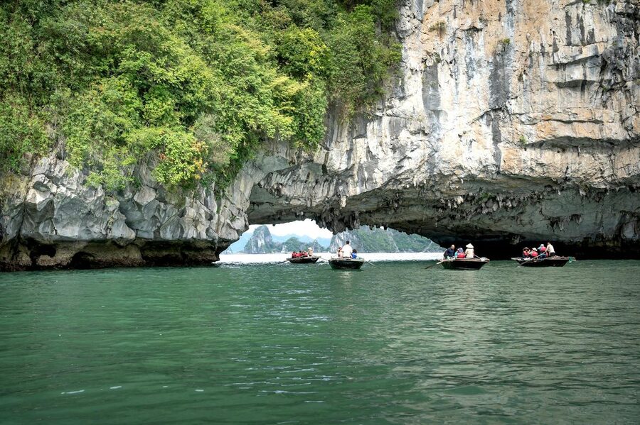 Boats sailing under rock formation in Ha Long Bay Vietnam