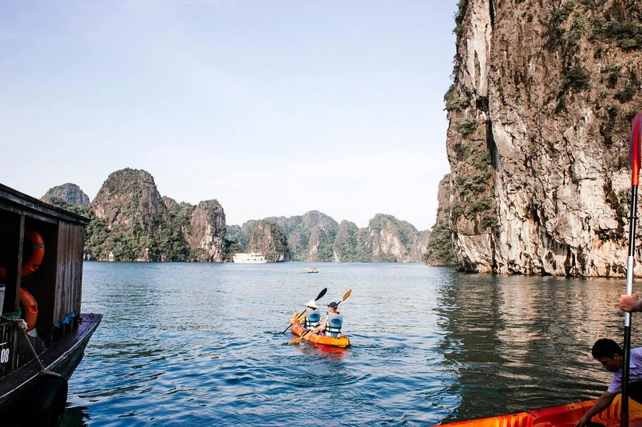 Two people kayaking through limestone karsts in Halong Bay