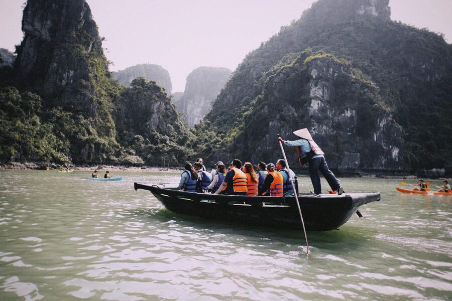 Tourists in life jackets on rowboat through karst landscape Vietnam